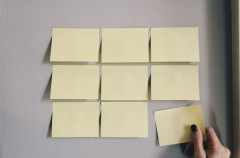 neuf post-it sur trois lignes, collés sur un mur, celui du bas à droite dans une main féminine, par Kelly Sikkema sur Unsplash.com