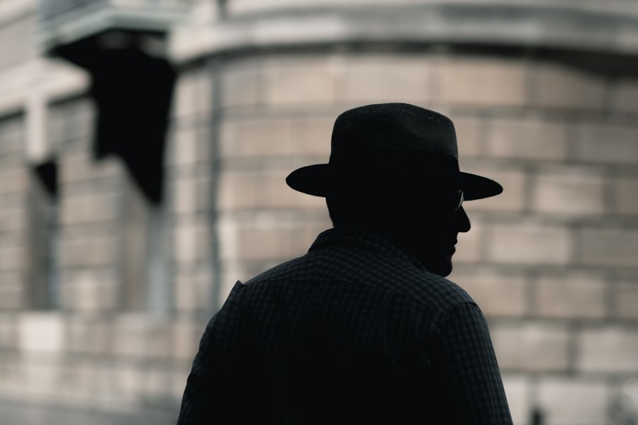 buste d’homme avec un fedora et des lunettes, de 3/4 dos et à contre-jour dans la rue, par Craig Whitehead sur Unsplash.com